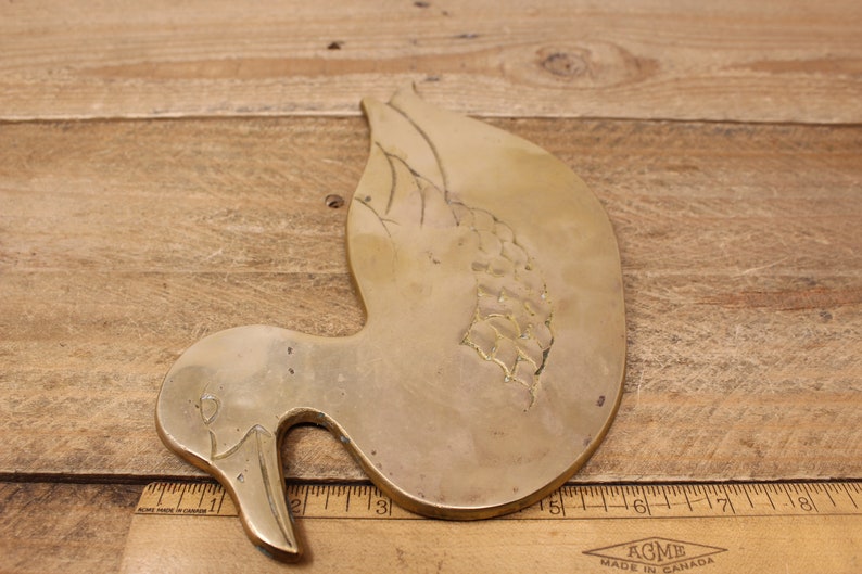 Pode incluir: Uma decora&ccedil;&atilde;o de parede de pato de lat&atilde;o com um design gravado detalhado. O pato est&aacute; em uma pose de voo com a cabe&ccedil;a virada para o lado. O pato mede aproximadamente 18 cm de comprimento.