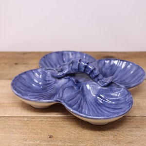 May include: A blue and white ceramic serving dish shaped like a seashell with a shrimp handle. The dish has three sections.