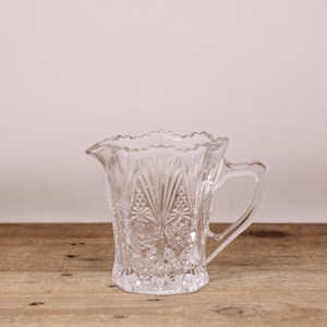 Peut inclure: Un pichet en verre transparent avec un motif décoratif. Le pichet a une poignée et une large ouverture.