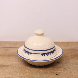 May include: White ceramic butter dish with a blue and white geometric design. The dish has a lid and a base.