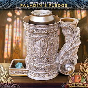 May include: A white and gold metal dice tower and storage container with a shield design. The tower has a removable top for storing a can. The container has a small tray for dice. The container is decorated with a gold and white ornate design. The container has the text "Paladin's Pledge" on the top.