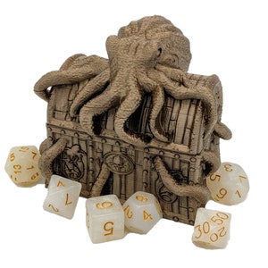 Puede incluir: Un cofre del tesoro de madera marrón con una tapa de pulpo. El cofre está rodeado de dados blancos con números dorados.