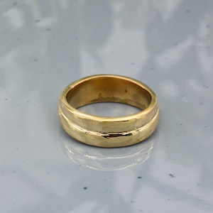 May include: A gold ring with a double-band design. The ring has a smooth, polished finish and a warm, yellow hue. The ring is a classic piece of jewelry.