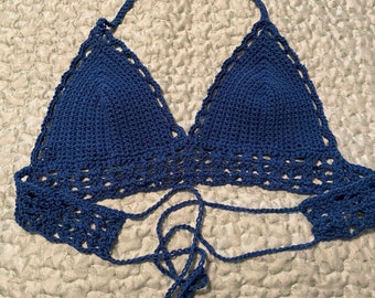 Op de afbeelding: Een blauwe gehaakte haltertop met een strik sluiting. De top is gemaakt van een delicate, opengeweven stof.
