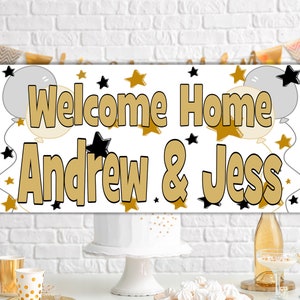 Puede incluir: Una pancarta blanca con estrellas doradas y negras y globos. La pancarta dice "Welcome Home Andrew & Jess".