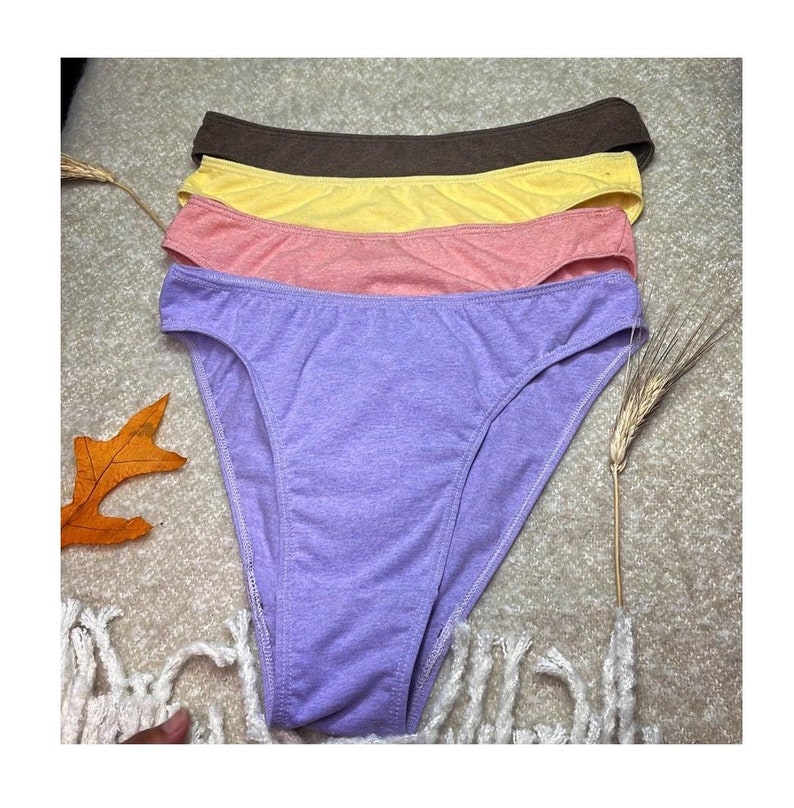 May include: Four pairs of underwear in different colors: purple, pink, yellow, and brown. The underwear is made of a soft, stretchy fabric.