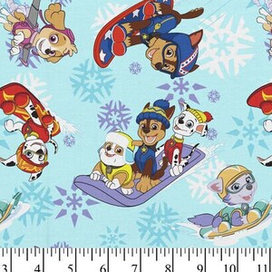 May include: Pale blue fabric with a repeating pattern of cartoon dogs on snowboards and sleds, with snowflakes. The dogs are in various poses, wearing helmets and winter gear. Suitable for children's crafts and sewing.
