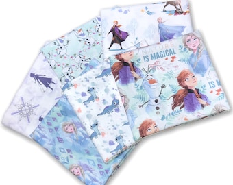 May include: A set of six fabric squares featuring characters from the animated film Frozen II. The squares feature various designs, including a blue and white snowflake pattern, a green and white pattern with Olaf and snowmen, a white and blue pattern with Anna and Elsa, and a white and blue pattern with a salamander. The text "Nature is Magical" is printed on one of the squares.