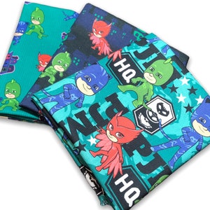 May include: Three fabric squares featuring the characters from the children's television show, 'PJ Masks'. The fabric squares are green, black, and blue with white stars. The characters are Gekko, Owlette, and Catboy. The text 'HQ' is printed on the fabric.
