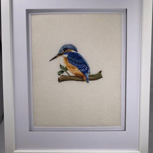 May include: A framed embroidery depicting a blue and orange kingfisher perched on a branch with green leaves.