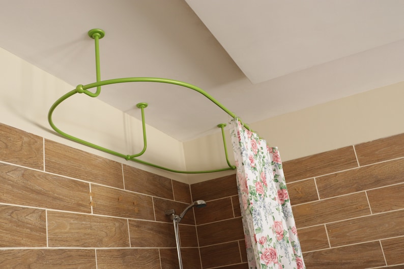 May include: A green curved shower curtain rod installed on a white ceiling. The rod is attached to the ceiling with four white brackets. A floral shower curtain hangs from the rod.