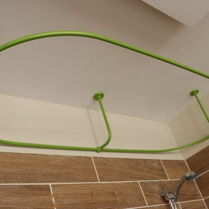 May include: A green metal shower curtain rod with a curved design, installed on a white ceiling. The rod is attached to the ceiling with four metal brackets.