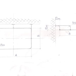 Puede incluir: Un diagrama dibujado a mano de una forma rectangular con esquinas redondeadas. La forma tiene 12 cm de ancho y 12 cm de alto. El diagrama incluye medidas para las esquinas redondeadas, que son R5 cm.
