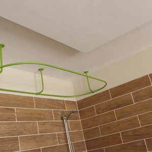 May include: A green metal shower curtain rod is installed in a bathroom. The rod is curved and has three supports. The rod is mounted to the ceiling.