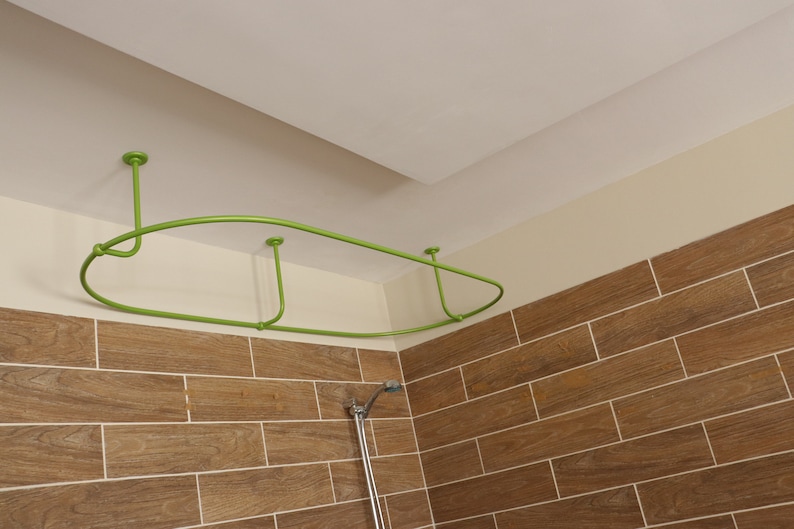 May include: A green metal shower curtain rod is installed in a bathroom. The rod is curved and has three supports. The rod is mounted to the ceiling.