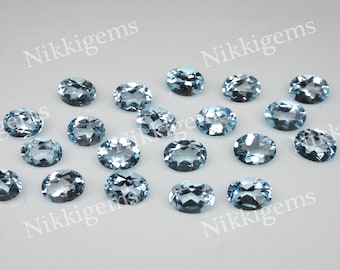 May include: A collection of 18 oval-shaped, light blue gemstones. The gemstones are smooth and polished, with a slight sparkle.