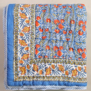 May include: A blue and white floral quilt featuring orange flowers and yellow leaves. The quilt has a blue border with a striped pattern and a white and yellow floral border.