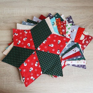 Könnte beinhalten: Ein Set mit 12 Stoffuntersetzern mit einem Sternburst-Design in Grün, Rot und Weiß mit Schneeflocken und Schneemännern. Die Untersetzer sind aus Baumwollstoff und perfekt, um Ihrer Einrichtung einen festlichen Touch zu verleihen.