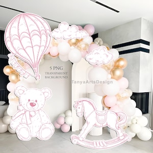 May include: Pink and white illustrations of a hot air balloon, teddy bear, rocking horse, and clouds. The text "5 PNG TRANSPARENT BACKGROUND" is visible. A balloon arch in white, pink, and gold completes the scene.