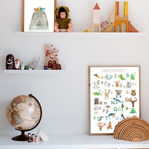 May include: A colorful alphabet poster with illustrations of animals for each letter. The poster is framed and hanging on a white wall above a shelf with wooden toys and a globe.