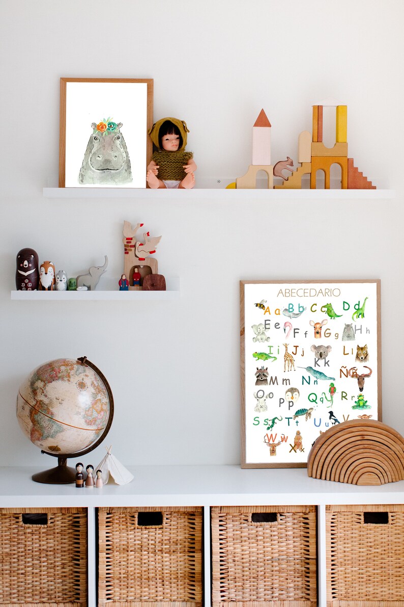 May include: A colorful alphabet poster with illustrations of animals for each letter. The poster is framed and hanging on a white wall above a shelf with wooden toys and a globe.