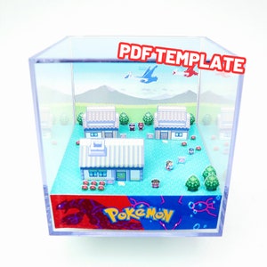 Può includere: Un diorama 3D di un villaggio Pokémon con case, alberi e personaggi. Il diorama è all'interno di un cubo trasparente con un logo Pokémon blu e rosso sul fondo.