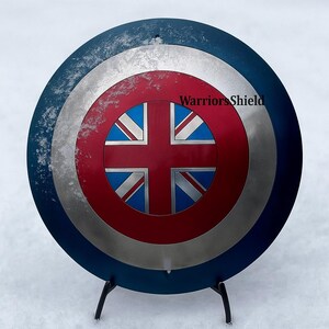 May include: A round shield with a blue outer ring, a silver middle ring, and a red center. The center features a Union Jack design. The text "WarriorsShield" is visible on the shield.
