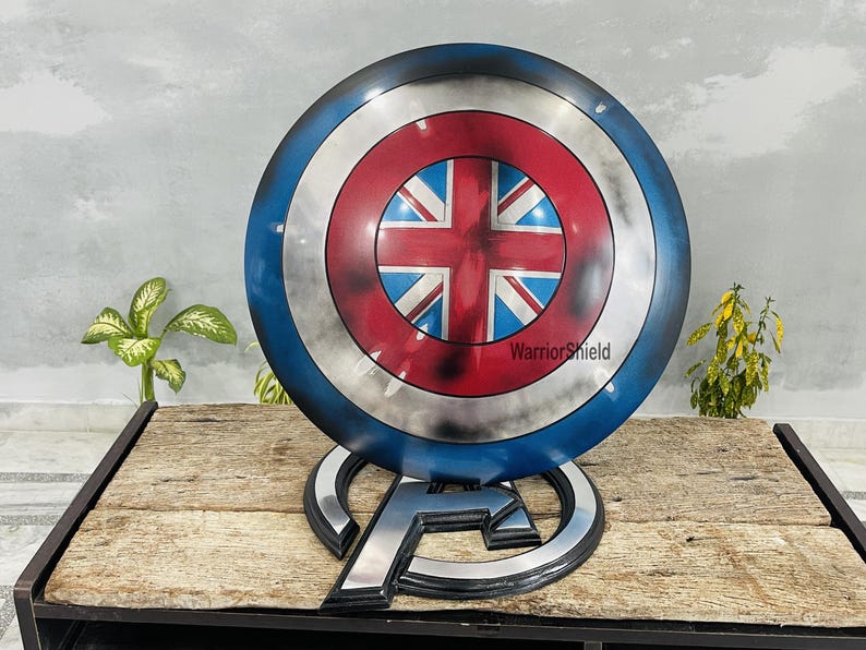 May include: A blue, red, and white Captain America shield with a Union Jack design in the center. The shield is on a stand with the letter "A" on it. The text "WarriorShield" is visible on the shield.