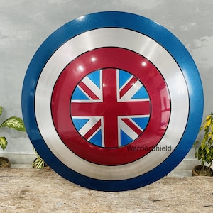 May include: A blue, white, and red Captain America shield with a Union Jack design in the center. The shield is made of metal and has a shiny finish. The text "WarriorShield" is printed on the shield.