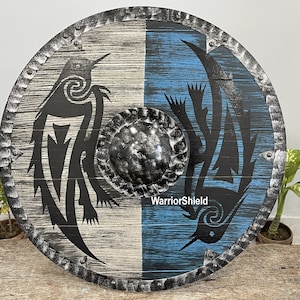 May include: A round wooden shield with a black and white design on one side and a blue and black design on the other side. The shield has a metal rim with rivets and a metal center boss. The text "WarriorShield" is printed on the shield.