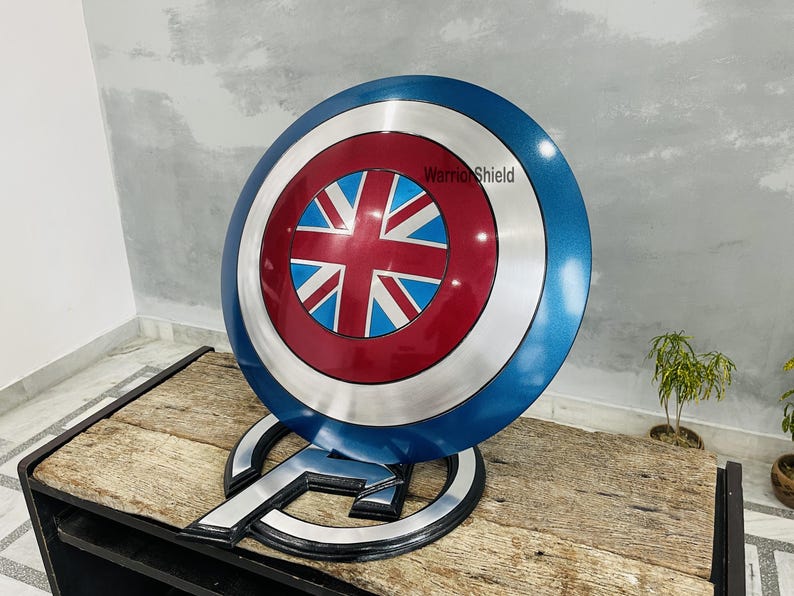 May include: A blue and red Captain America shield with a Union Jack design in the center. The shield is on a wooden stand with the text "Warrior Shield" on the shield.