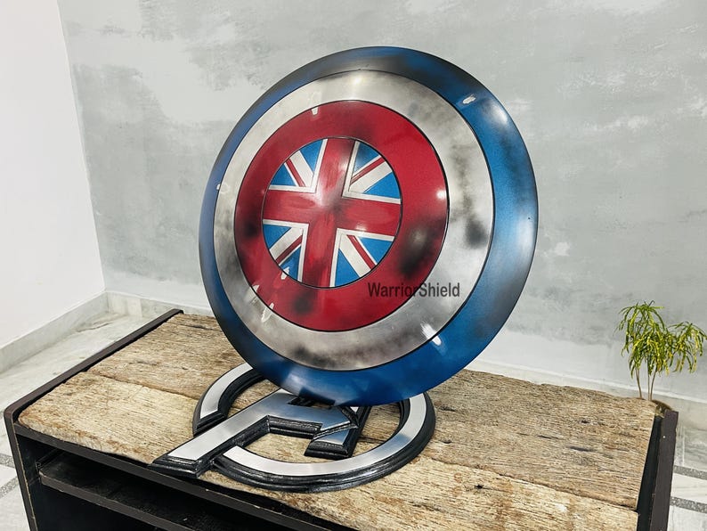 May include: A red, white, and blue Captain America shield with a Union Jack design in the center. The shield is on a stand with the text "Warrior Shield" on it.