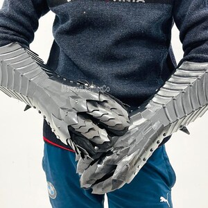 May include: A pair of silver metal gauntlets with a dragon scale design. The gauntlets are worn on both hands and have a pointed tip on the back of the hand.