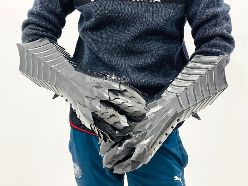 May include: A pair of silver metal gauntlets with a dragon scale design. The gauntlets are worn on both hands and have a pointed tip on the back of the hand.
