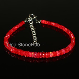 May include: A red opal gemstone bracelet with a silver clasp. The bracelet is made of small, round beads.