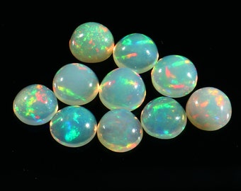May include: Ten round, iridescent opal cabochons in various shades of green, blue, and pink. The opals are smooth and polished, with a high gloss finish.