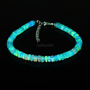 May include: A delicate necklace made of small, iridescent opal beads in shades of blue and green. The necklace has a silver clasp and is approximately 18 inches long.