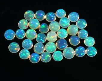 May include: A collection of round, iridescent opal cabochons in various shades of green and blue. The opals are smooth and polished, with a high lustre.