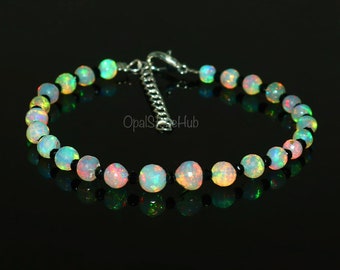 May include: A bracelet made of alternating black and iridescent opal beads. The bracelet has a silver clasp.