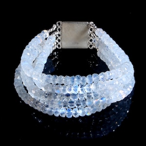 Op de afbeelding: Een zilveren armband met meerdere rijen witte maansteen kralen. De armband heeft een zilveren sluiting.