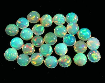 May include: A collection of 20 round, iridescent opal cabochons. The opals are a pale green colour with flashes of rainbow.