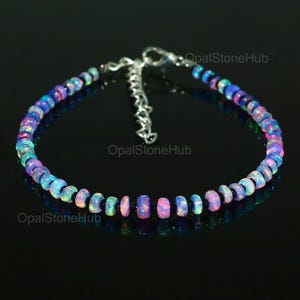 Peut inclure: Un bracelet délicat composé de perles d'opale irisées et de perles noires. Le bracelet est doté d'un fermoir en chaîne argentée.