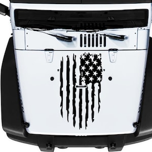 Peut inclure: Un autocollant de drapeau américain en détresse noir et blanc pour un Jeep Wrangler. L'autocollant est appliqué sur la calandre avant du véhicule.