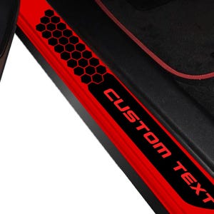 May include: Red car door sill protector with black honeycomb pattern and the words "CUSTOM TEXT" in red. The car door sill is a protective accessory for the vehicle's interior.