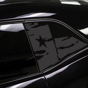 May include: A black car with a gray and white decal of a star on the back window.
