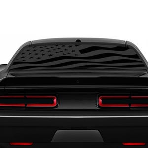 May include: Black car with a rear window decal of an American flag. The flag is in black and white and is displayed on the rear window of a black car.