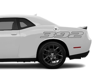 May include: A white Dodge Challenger with black 392 decals on the rear quarter panel. The car has black wheels and a black rear spoiler.