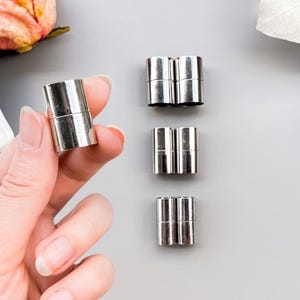 Peut inclure: Un ensemble de fermoirs magnétiques cylindriques de couleur argentée pour la création de bijoux. Les composants métalliques présentent une finition lisse et polie avec une couture visible là où les deux moitiés magnétiques se rejoignent.