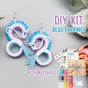 May include: DIY bead earring kit featuring two dragon-shaped earrings. The earrings are white, purple, and blue beaded with silver hooks. The kit includes beads, instructions, and a gift box with a silver ribbon.