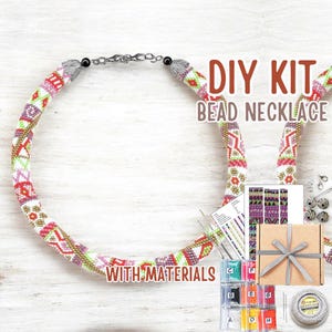 May include: DIY bead necklace kit with materials. The necklace is a colorful, beaded design in red, pink, green, and white. The kit includes beads, string, and a gift box with a gray ribbon.